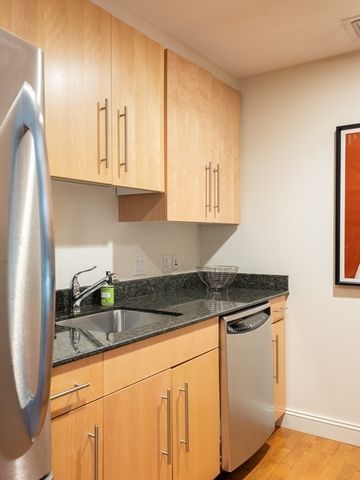a kitchen with granite countertop a sink a stove and cabinets