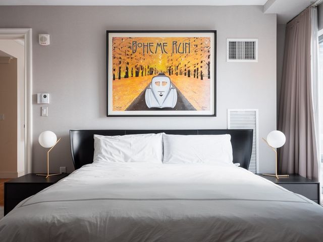 a bedroom with a bed and painting on the wall