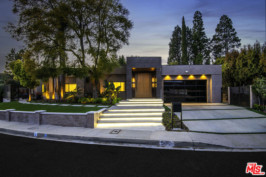 a front view of a house with a garden and a tree