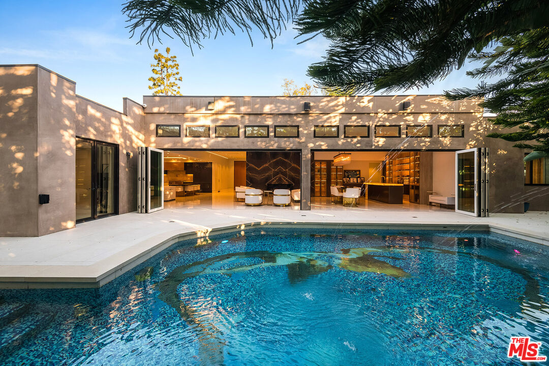16601 Park Ln Circle Los Angeles, CA 90049 - Photo 25 of 69 a view of a swimming pool with a lawn chairs under an umbrella