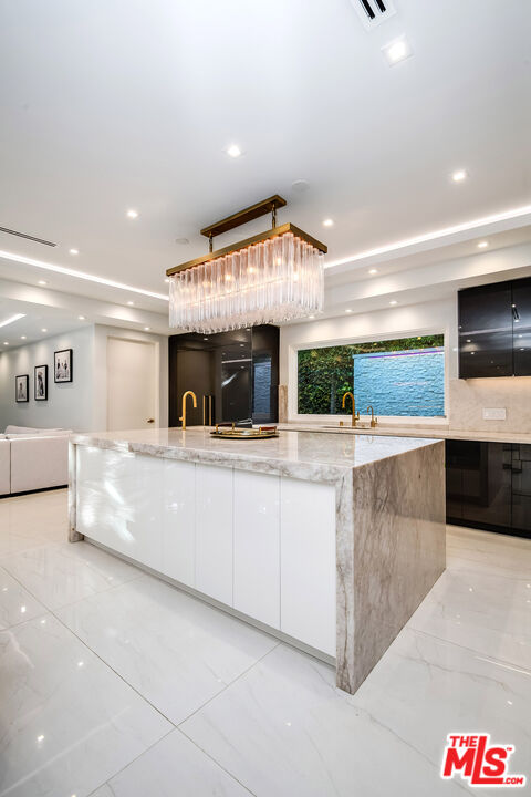 16601 Park Ln Circle Los Angeles, CA 90049 - Photo 29 of 69 a large kitchen with stainless steel appliances kitchen island a large counter top and a view of living room