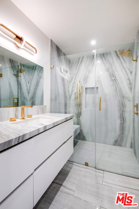 16601 Park Ln Circle Los Angeles, CA 90049 - Photo 36 of 69 a bathroom with a granite countertop sink a mirror and shower