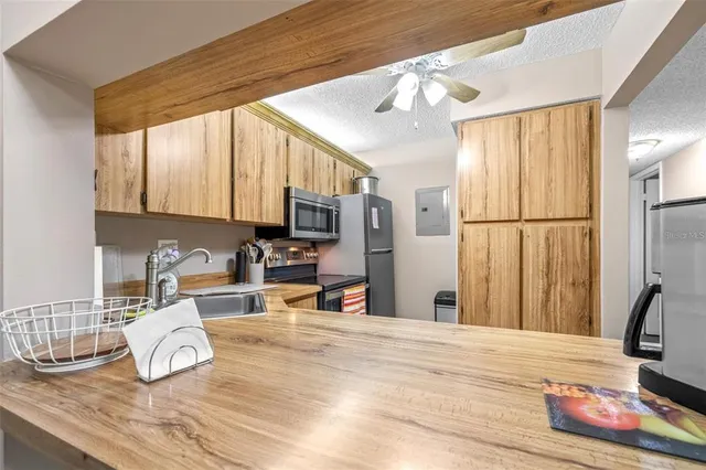 a kitchen with granite countertop a refrigerator a stove a sink a counter space and cabinets