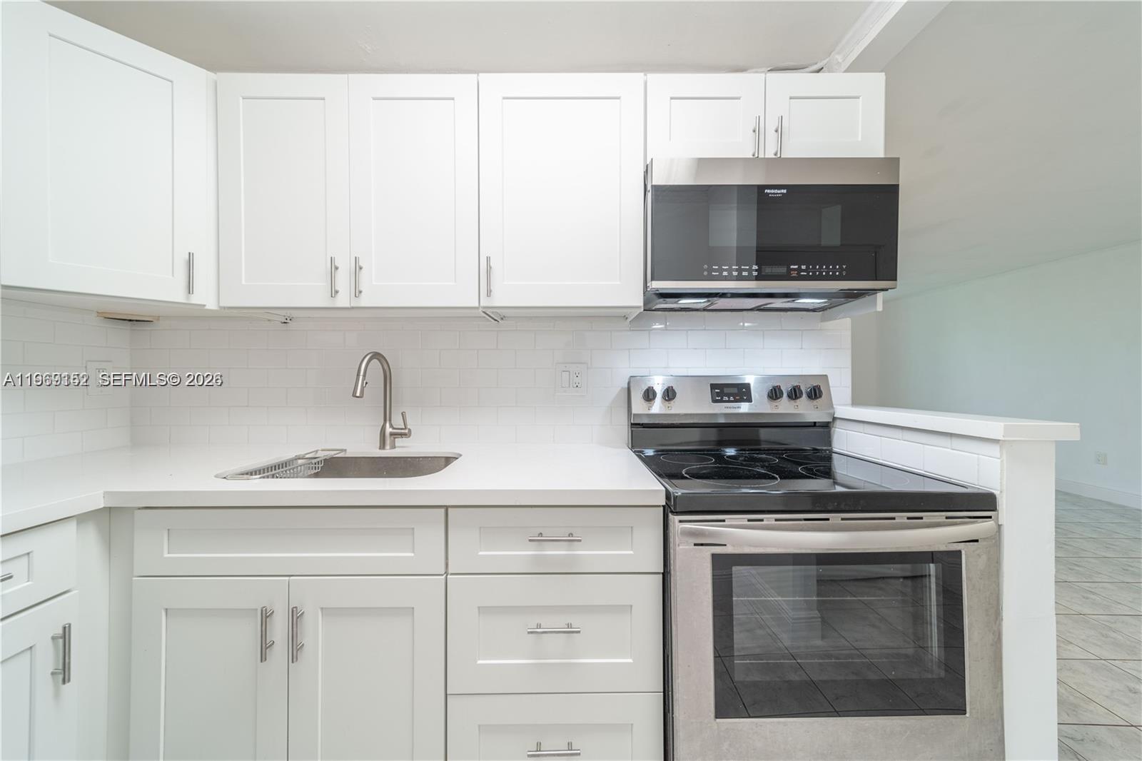 8501 Northwest 8th Street, Unit 110 Miami, FL 33126 - Photo 5 of 21 a kitchen with stainless steel appliances granite countertop white cabinets and a stove top oven