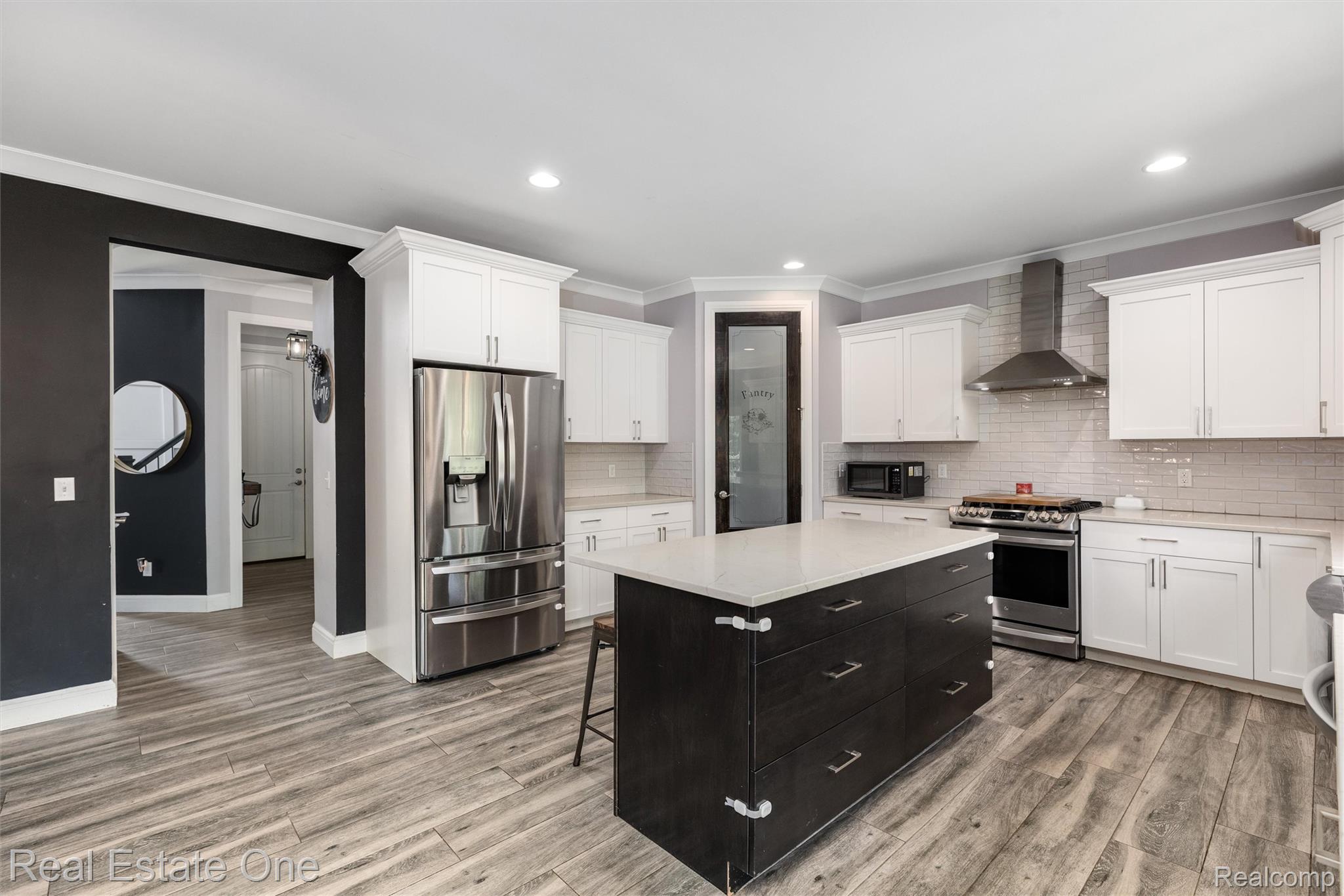 2983 28 Mile Road Washington, MI 48094 - Photo 10 of 54 Modern kitchen featuring a dark island with a light countertop, stainless steel appliances, white cabinetry, wood-finish flooring, and recessed lighting