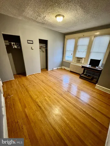 a view of an empty room with window and wooden floor