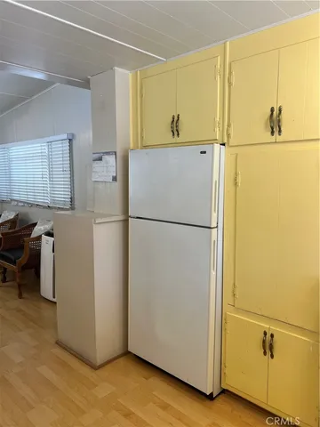 a utility room with refrigerator and wooden cabinets