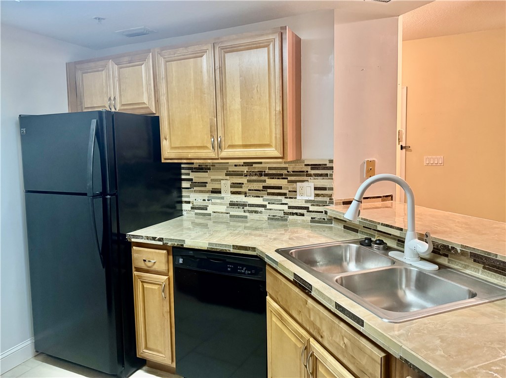 5060 Fairways Circle, Unit F207 Vero Beach, FL 32967 - Photo 10 of 14 a kitchen with a sink a refrigerator and cabinets