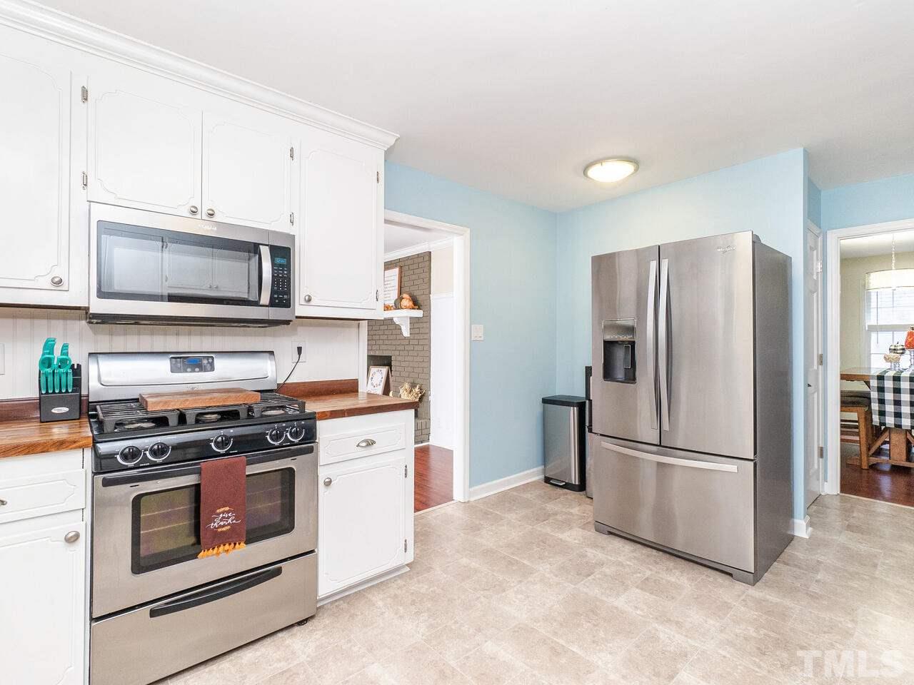 4313 Hopson Drive Raleigh, NC 27604 - Photo 11 of 30 a kitchen with stainless steel appliances white cabinets a stove a microwave and a refrigerator