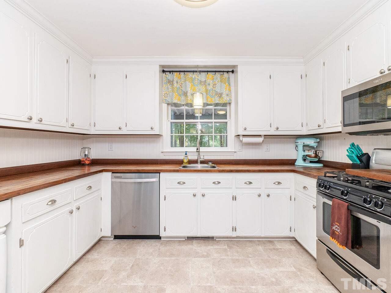 4313 Hopson Drive Raleigh, NC 27604 - Photo 10 of 30 a large white kitchen with granite countertop white cabinets a sink and dishwasher a stove with wooden floor