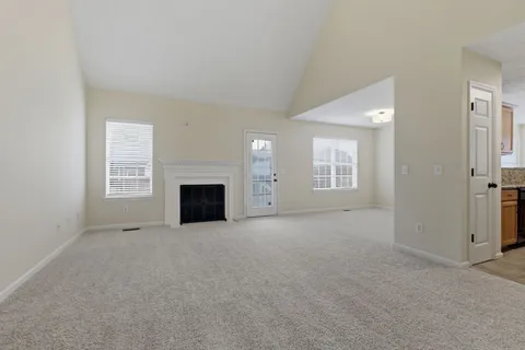 an empty room with windows and fireplace