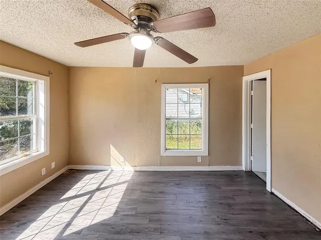a view of an empty room with a window and wooden floor