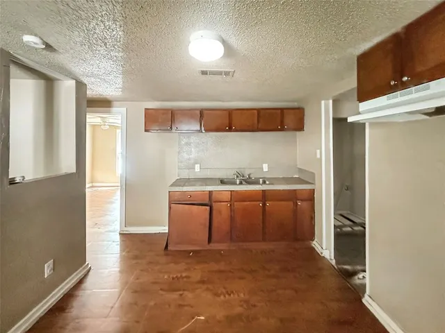 a room with granite countertop a sink and a refrigerator