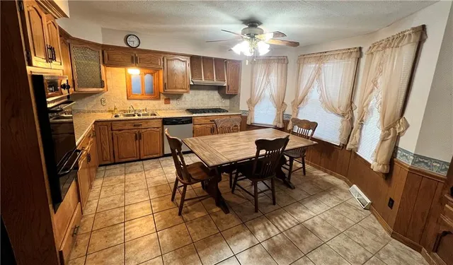 a kitchen with granite countertop stainless steel appliances a table chairs sink and cabinets