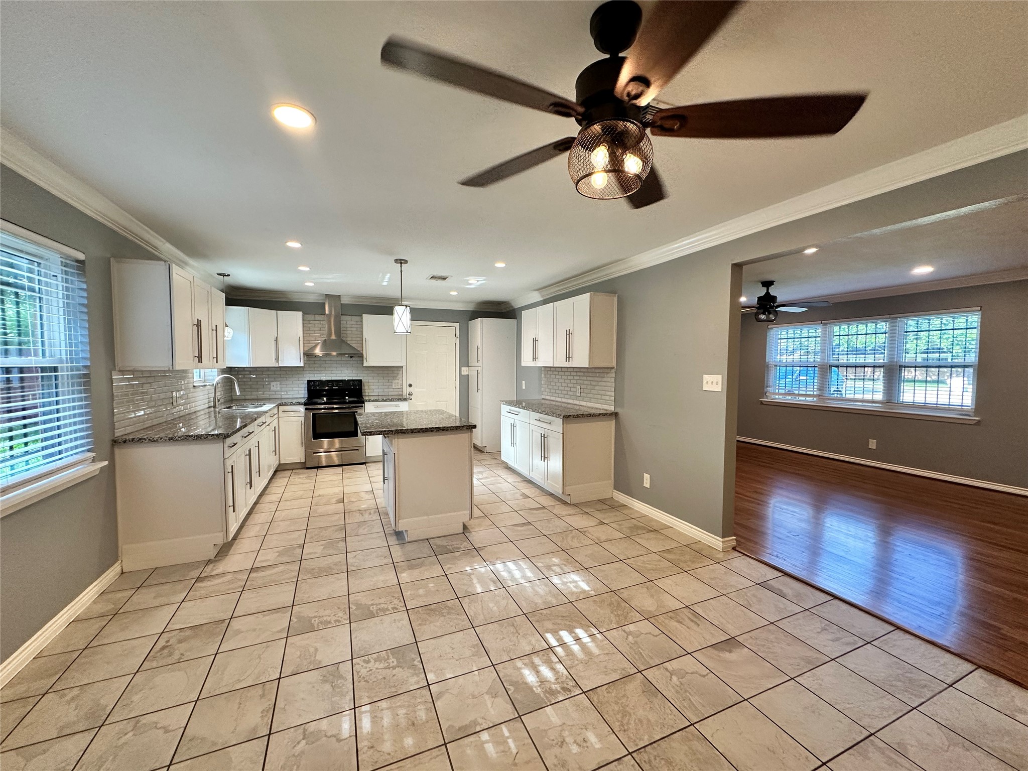 2206 South Houston Road Pasadena, TX 77502 - Photo 1 of 11 a large white kitchen with kitchen island a stove a sink dishwasher and white cabinets with wooden floor