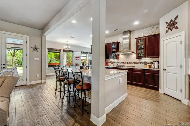 a kitchen with stainless steel appliances kitchen island granite countertop a stove a refrigerator a microwave a dining table and chairs with wooden floor