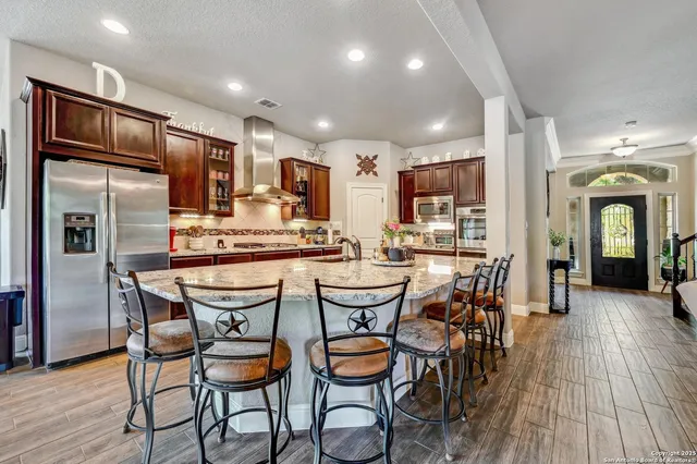 a kitchen with stainless steel appliances kitchen island granite countertop a dining table chairs refrigerator and sink