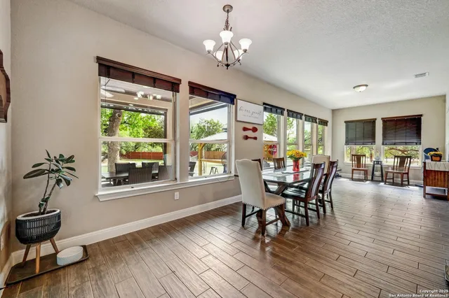 a dining room with wooden floor a chandelier a glass table and chairs