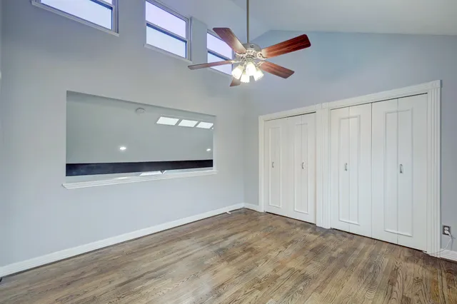 an empty room with wooden floor and ceiling fan