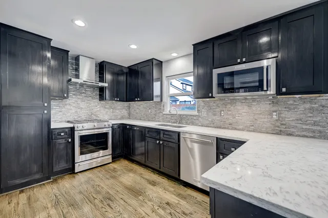 a kitchen with stainless steel appliances kitchen island granite countertop a sink stove and microwave
