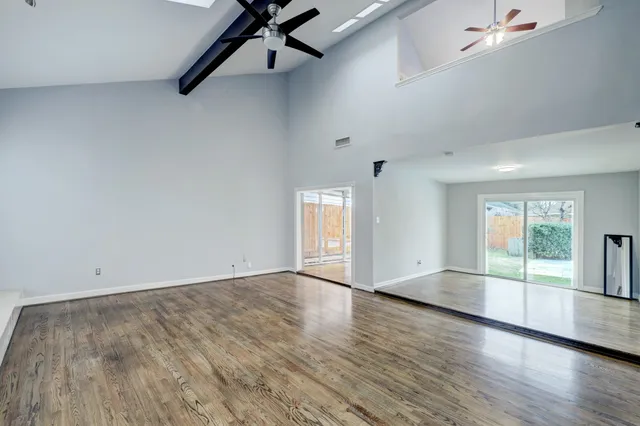 an empty room with windows fireplace and fans