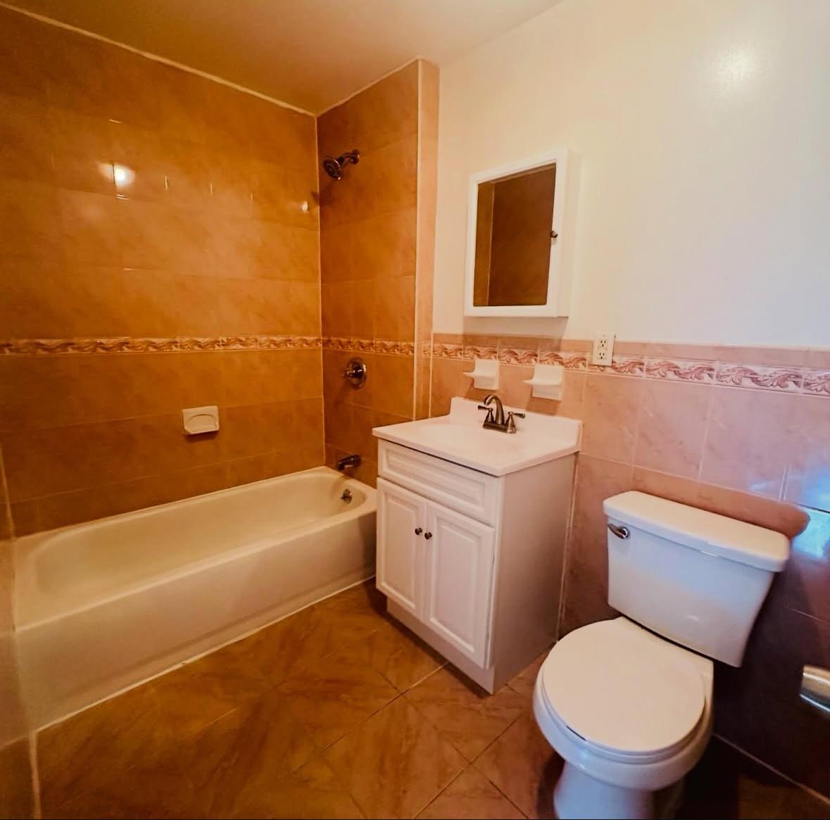1079 Willoughby Avenue Brooklyn, NY 11221 - Photo 11 of 19 Full bathroom featuring tile walls, tiled shower / bath combo, vanity, tile patterned floors, and toilet