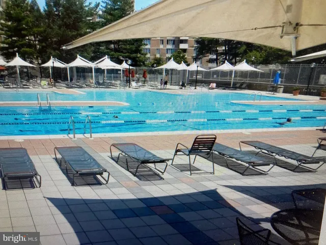 a view of a white house with a yard swimming pool and sitting area