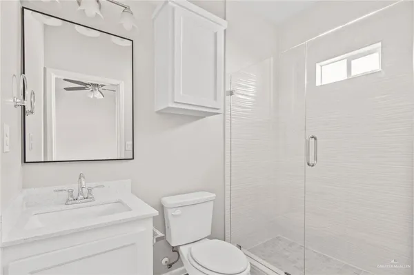 a bathroom with a toilet sink vanity granite and shower