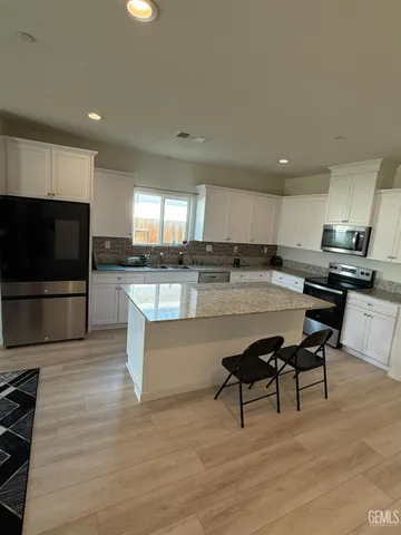 a kitchen with stainless steel appliances kitchen island granite countertop a stove a sink a refrigerator and a microwave