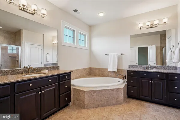 a bathroom with a tub a double vanity sink a mirror a lamp a window a bathtub and vanity