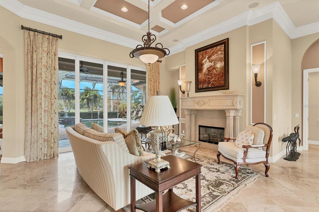7007 Portmarnock Place Lakewood Ranch, FL 34202 - Photo 13 of 92 a living room with furniture a fireplace and a chandelier