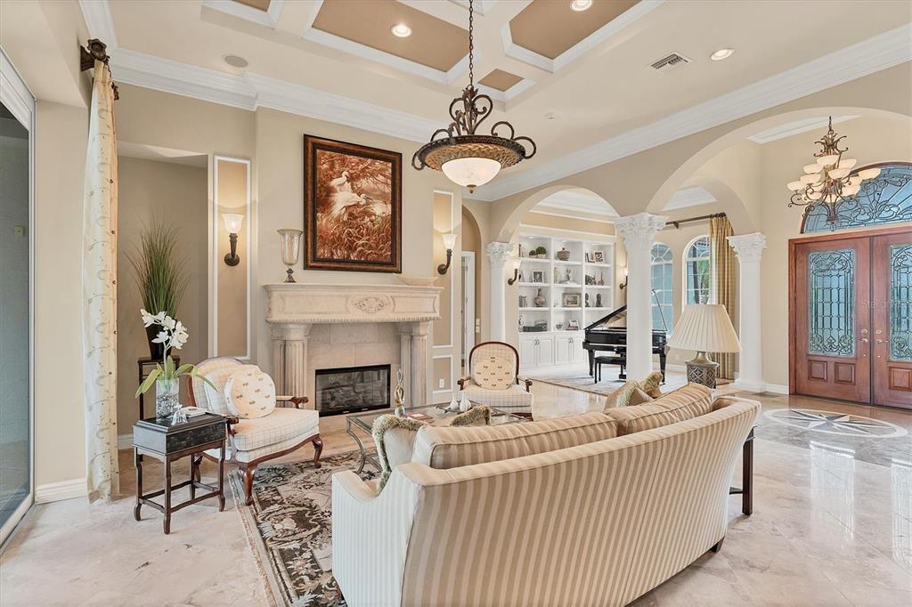 7007 Portmarnock Place Lakewood Ranch, FL 34202 - Photo 15 of 92 a living room with furniture a fireplace and a chandelier