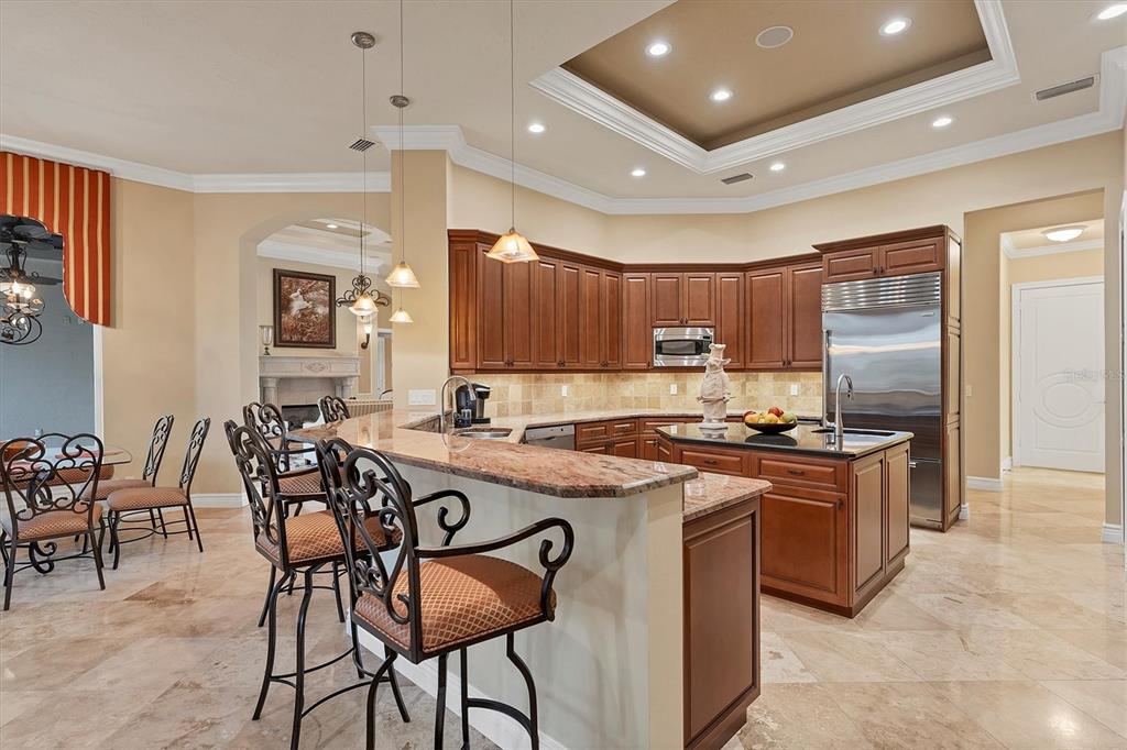7007 Portmarnock Place Lakewood Ranch, FL 34202 - Photo 21 of 92 a kitchen with stainless steel appliances granite countertop a stove top oven a sink dishwasher a dining table and chairs with wooden floor