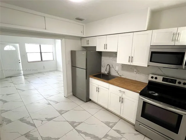 a kitchen with stainless steel appliances a refrigerator sink and microwave