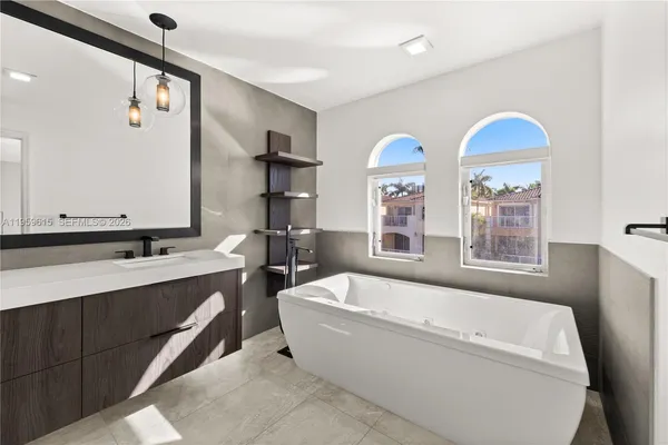 a bathroom with a tub a sink and a large mirror