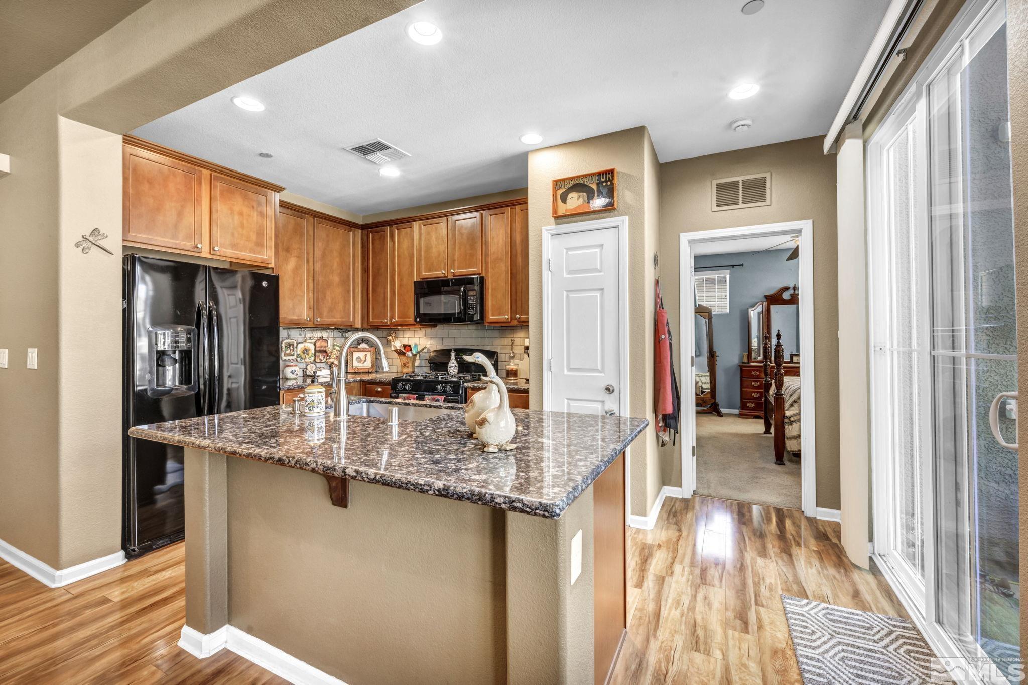1924 Wind Ranch Road, Unit C Reno, NV 89521 - Photo 13 of 27 a kitchen with stainless steel appliances granite countertop a refrigerator a sink and a stove with wooden floor
