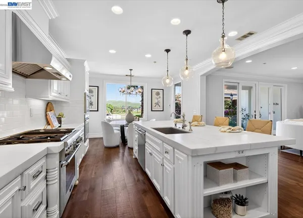 a kitchen with stainless steel appliances a stove a sink dishwasher and white cabinets with wooden floor