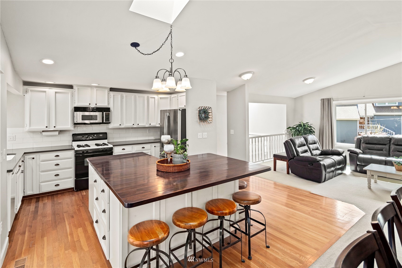 22613 Meridian Avenue South Bothell, WA 98021 - Photo 10 of 39 a kitchen with stainless steel appliances granite countertop a stove top oven a dining table and chairs with wooden floor
