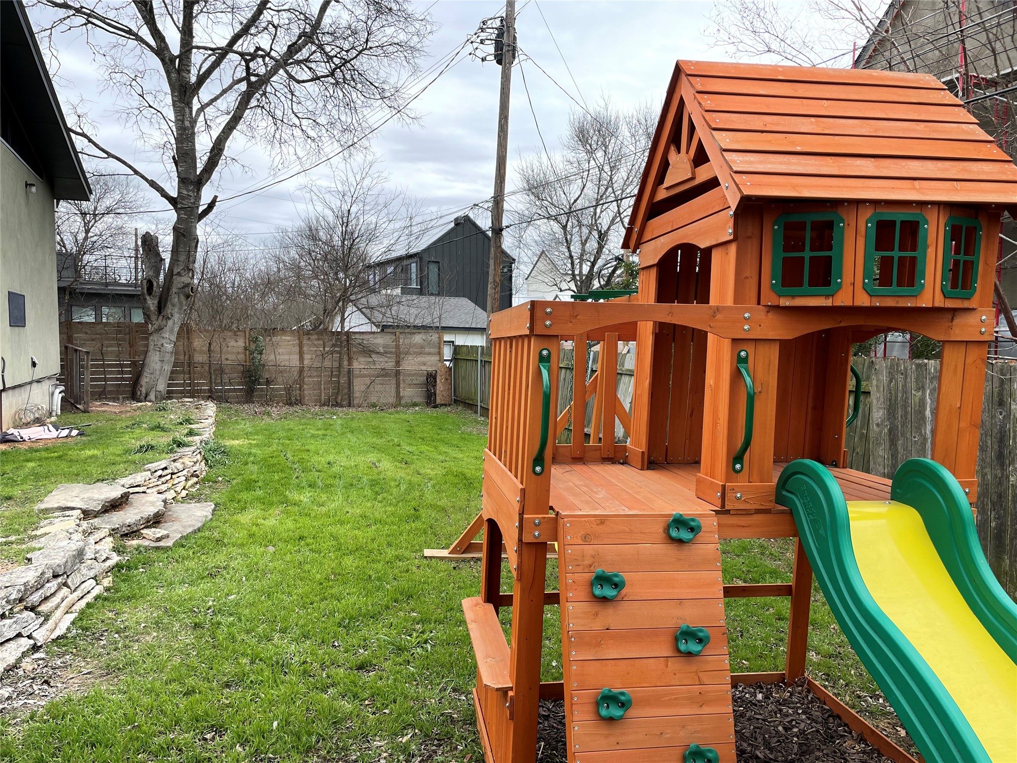 4619 Jinx Avenue, Unit A Austin, TX 78745 - Photo 19 of 21 Expansive backyard featuring a manicured lawn, a retaining wall crafted from natural stone, and mature trees