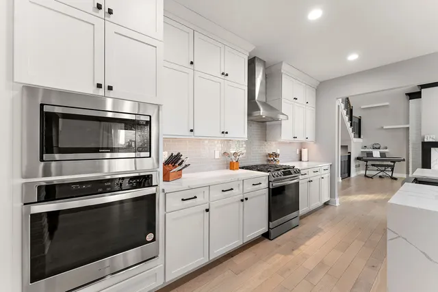 a kitchen with stainless steel appliances white cabinets and a stove top oven