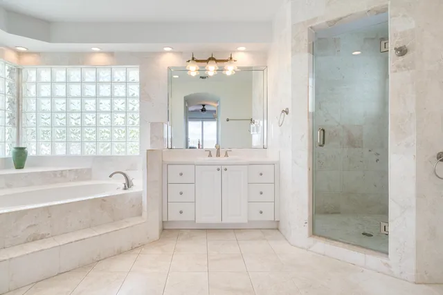 a spacious bathroom with a granite countertop sink a mirror a shower and a bathtub