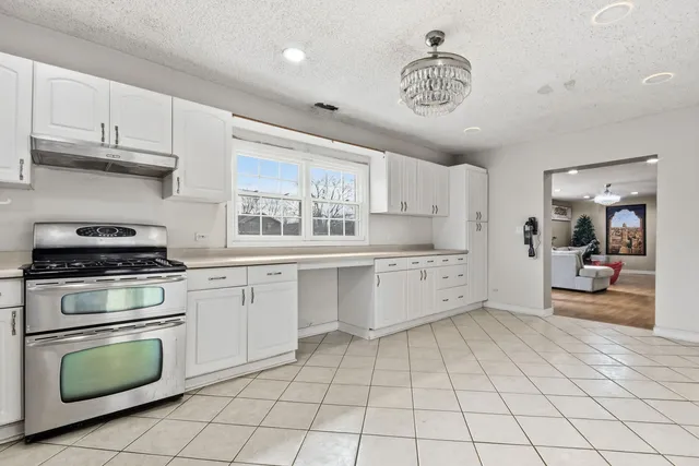 a kitchen with white cabinets a sink a window and appliances