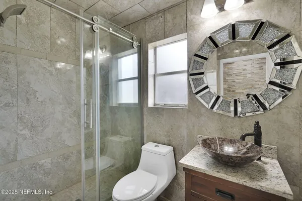 a bathroom with a granite countertop sink a toilet and shower