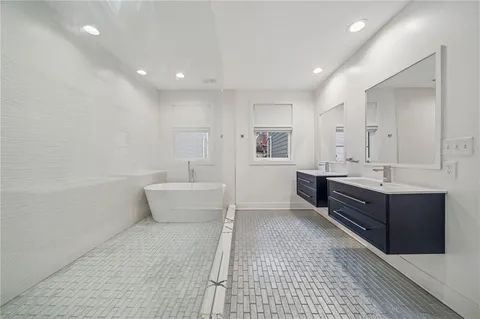 a bathroom with a double vanity sink a mirror and a bathtub