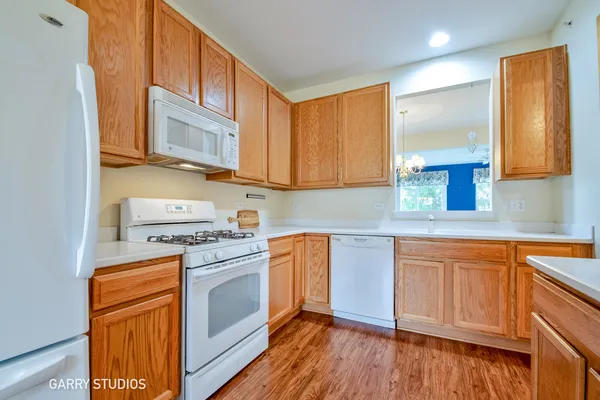 a kitchen with stainless steel appliances granite countertop wooden cabinets a stove a sink and dishwasher with wooden floor