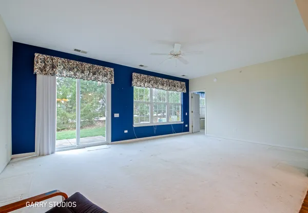 a view of a big room with windows and chandelier fan