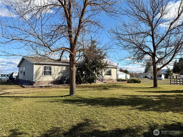 a view of a house with a big yard and large trees