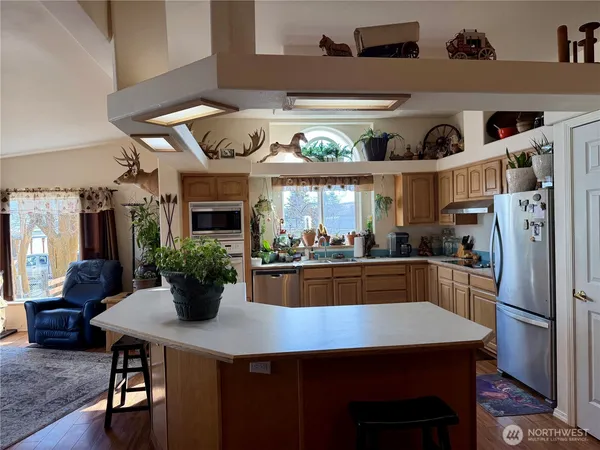 a kitchen with stainless steel appliances granite countertop a dining table chairs and refrigerator