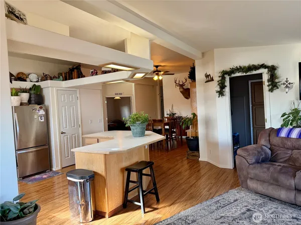 a living room with furniture a wooden floor and a refrigerator