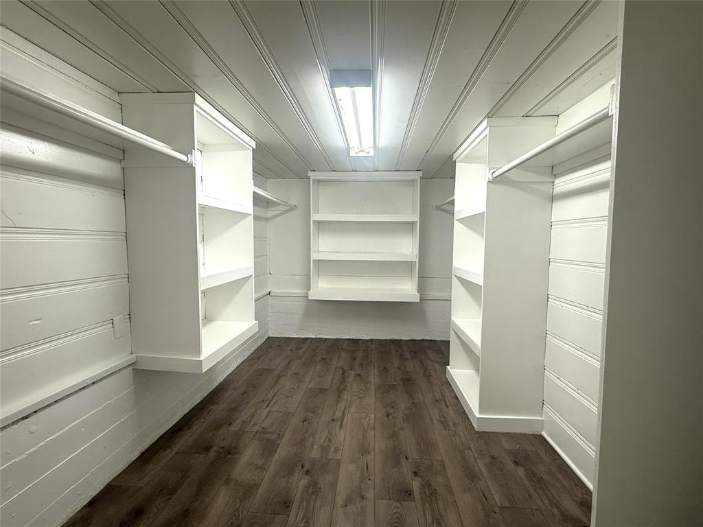 4718 Normandy Road Fort Worth, TX 76103 - Photo 23 of 26 Walk-in closet with wood-finish flooring, white shiplap walls, built-in shelving, hanging rods, and an overhead fluorescent light fixture